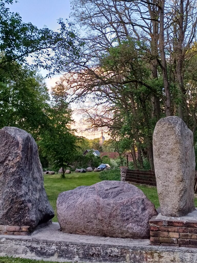 Geologischer Garten Stolzenhagen: Findlingssteine mit Dorfkirche Stolzenhagen im Hintergrund
